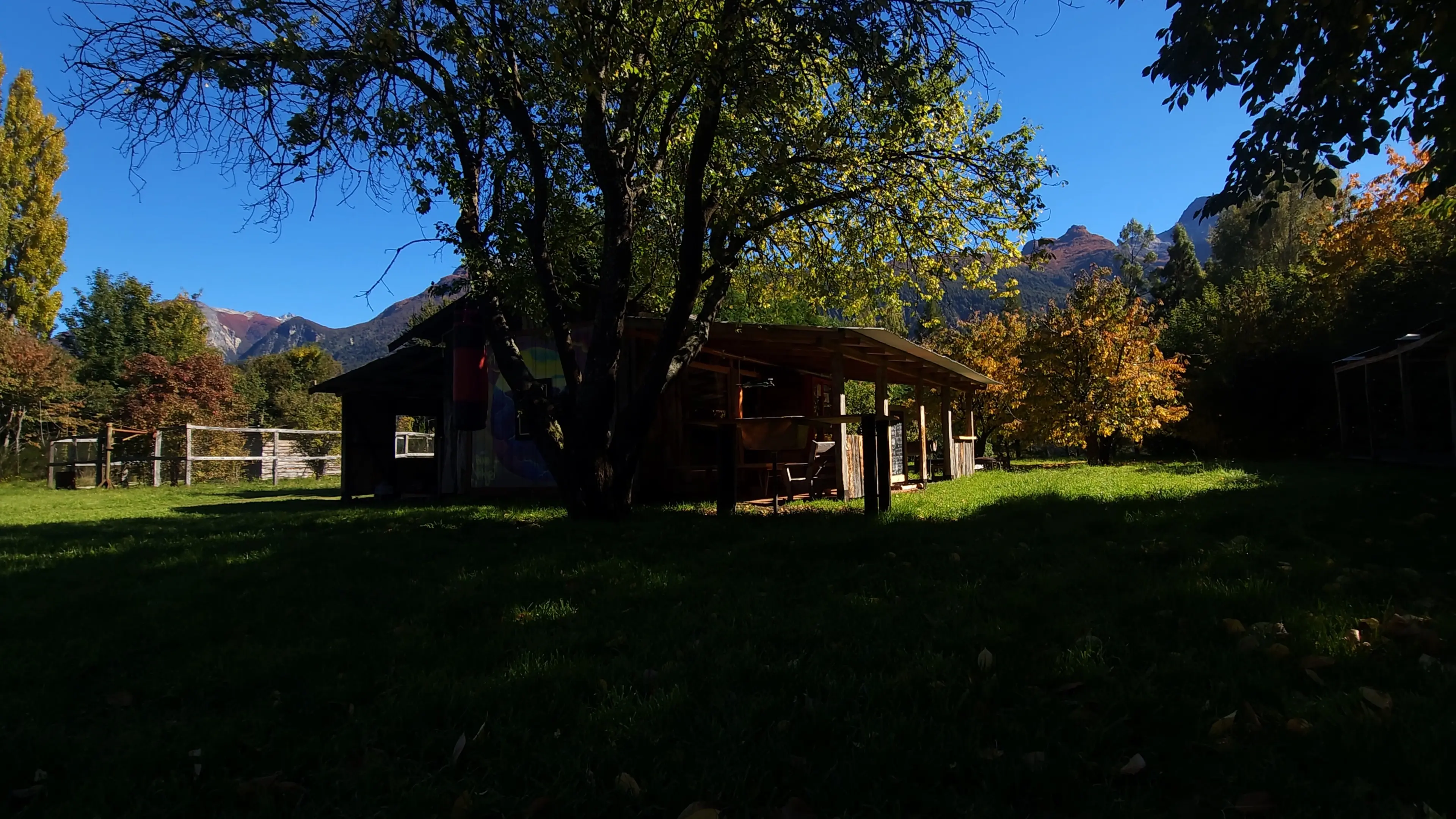 Quincho entre árboles de otoño, con la cordillera de fondo